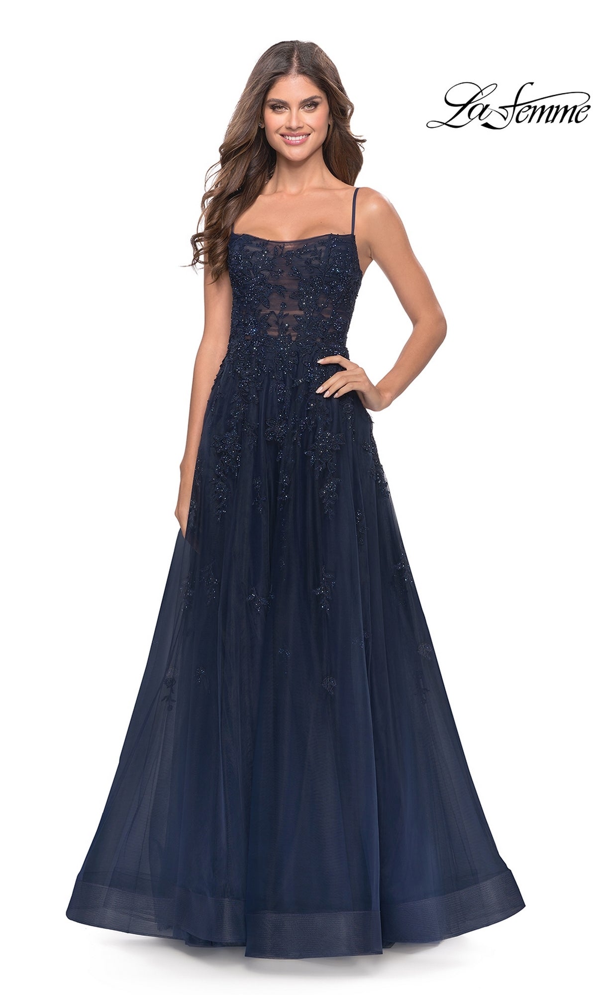 A woman stands and smiles in the La Femme Lace-Bodice Long A-Line Prom Dress 31381—navy blue, sleeveless, with an intricately embellished embroidered lace bodice.